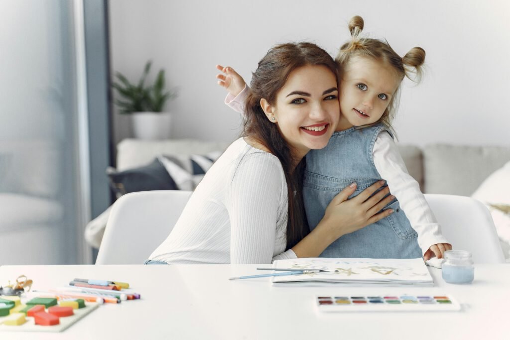 Mother and daughter bonding over watercolor painting indoors, capturing joy and togetherness.